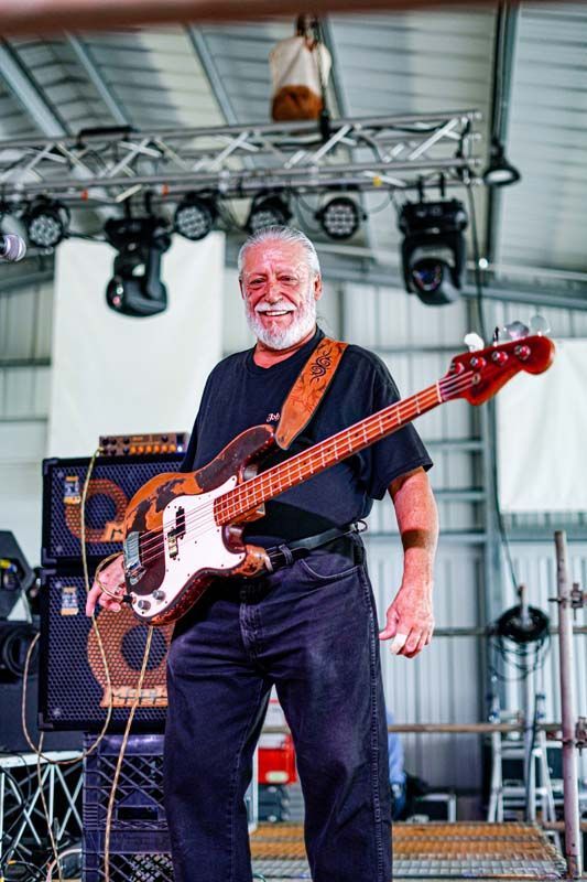A man is playing a bass guitar on a stage.