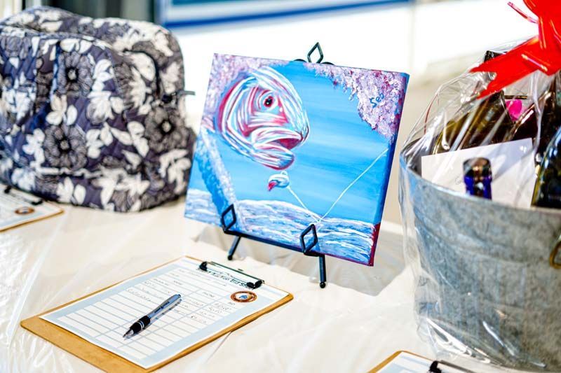 A painting of a fish is sitting on a table next to a clipboard and pen.