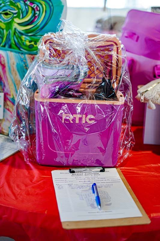A purple cooler is sitting on top of a red table next to a clipboard and pen.
