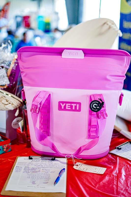 A pink yeti bag is sitting on a table next to a clipboard.
