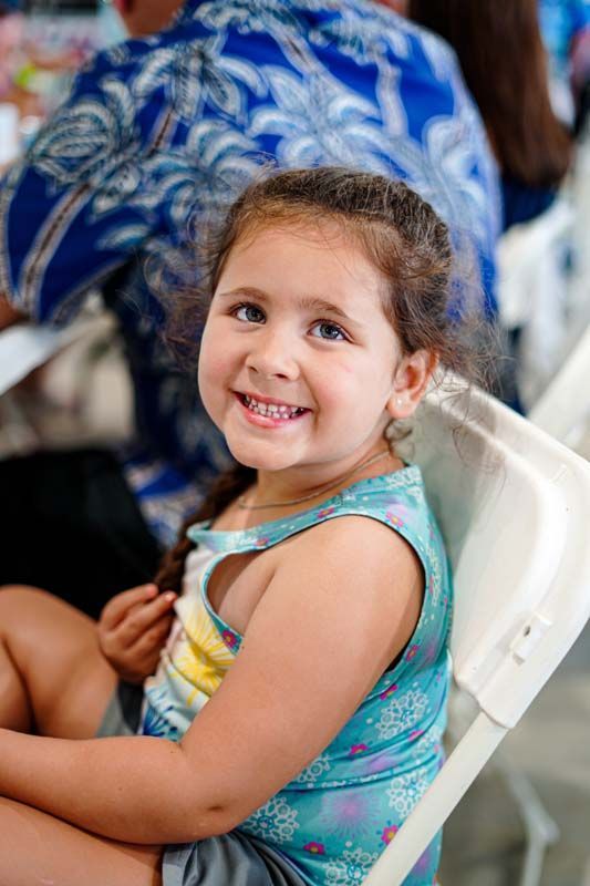 A little girl is sitting in a chair and smiling at the camera.