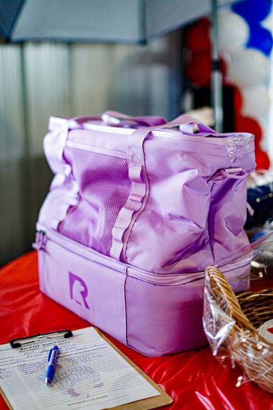 A purple bag is sitting on a table next to a clipboard and pen.