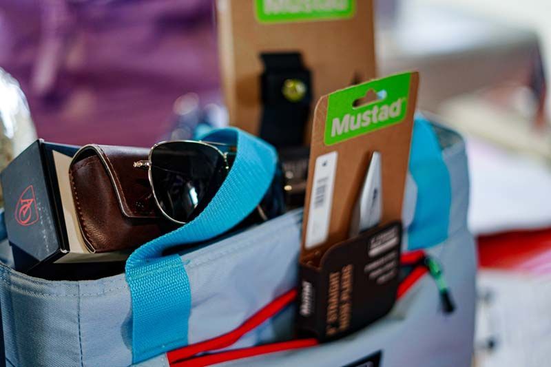 A cooler bag filled with sunglasses , a wallet , and a mustard tag.