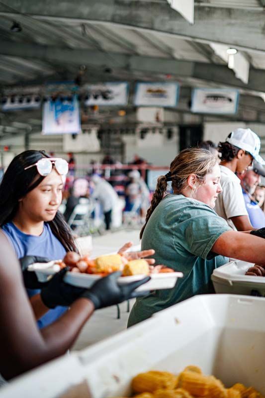 A group of people are standing around a table eating food.