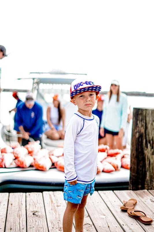 A young boy is standing on a dock next to a boat.