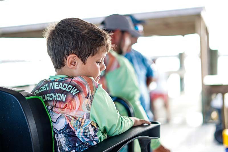 A young boy is sitting in a chair on a boat.