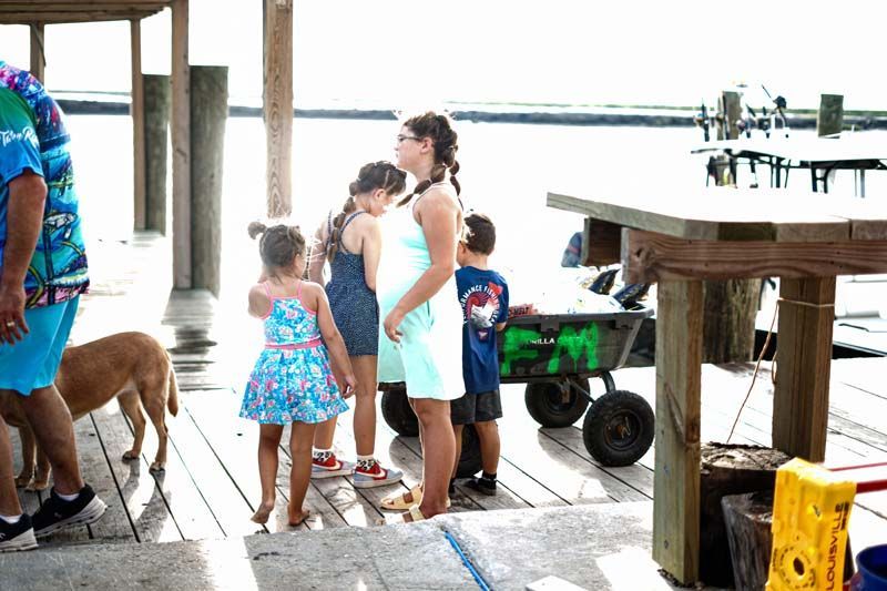A group of people standing on a dock next to a wagon.