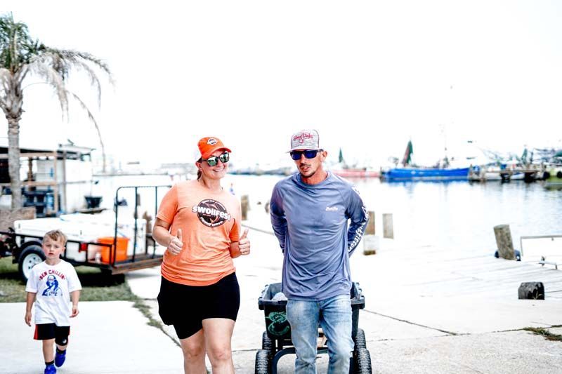 A man and a woman are walking down a sidewalk next to a body of water.