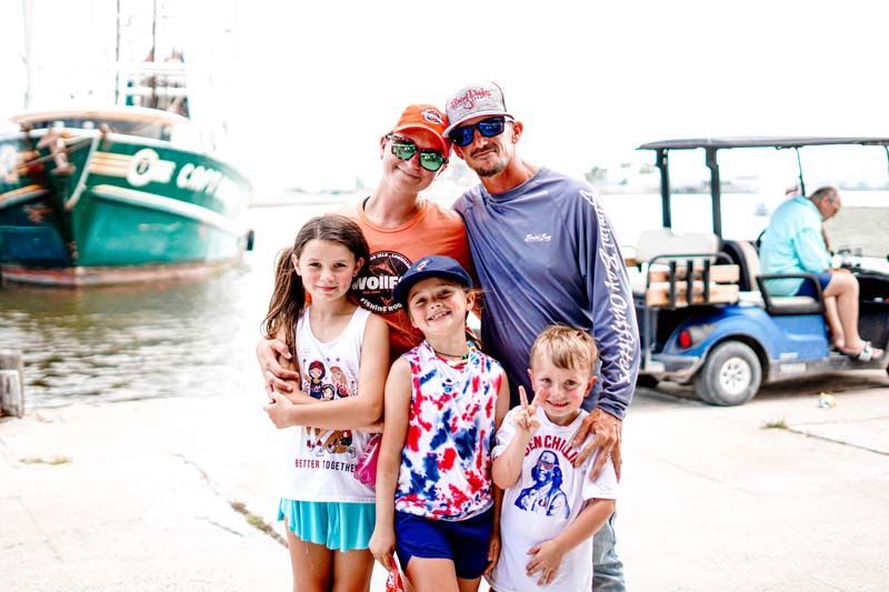 A family is posing for a picture in front of a boat.