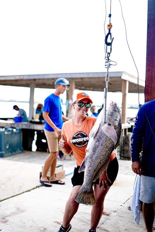 A woman is holding a large fish on a hook.
