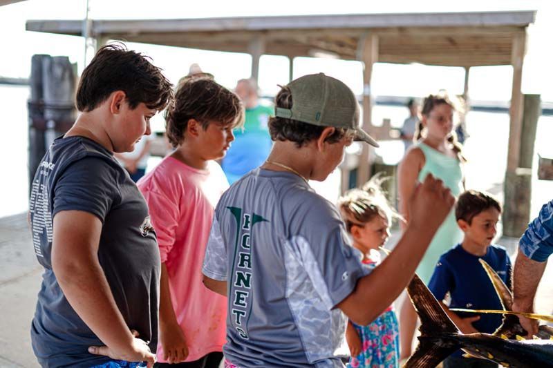 A group of children are looking at a large fish.