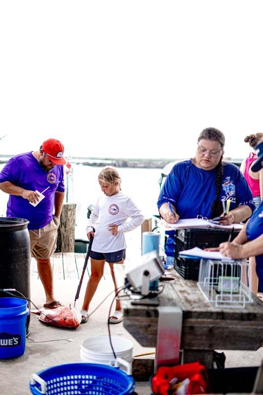 A group of people are standing around a wooden table.