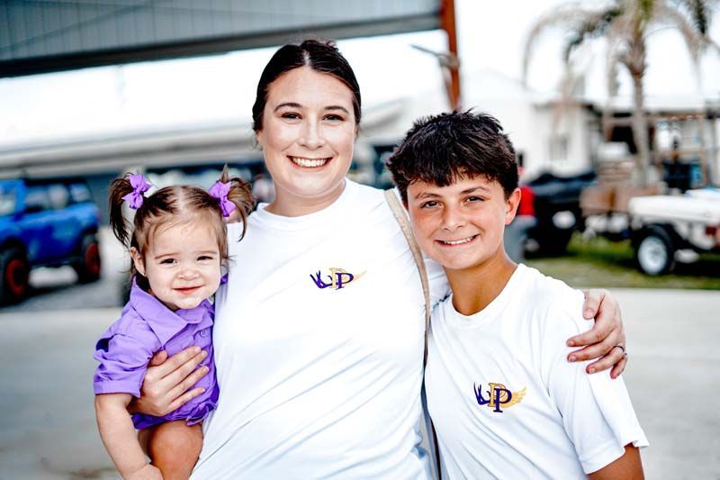 A woman is holding a little girl and a boy in her arms.
