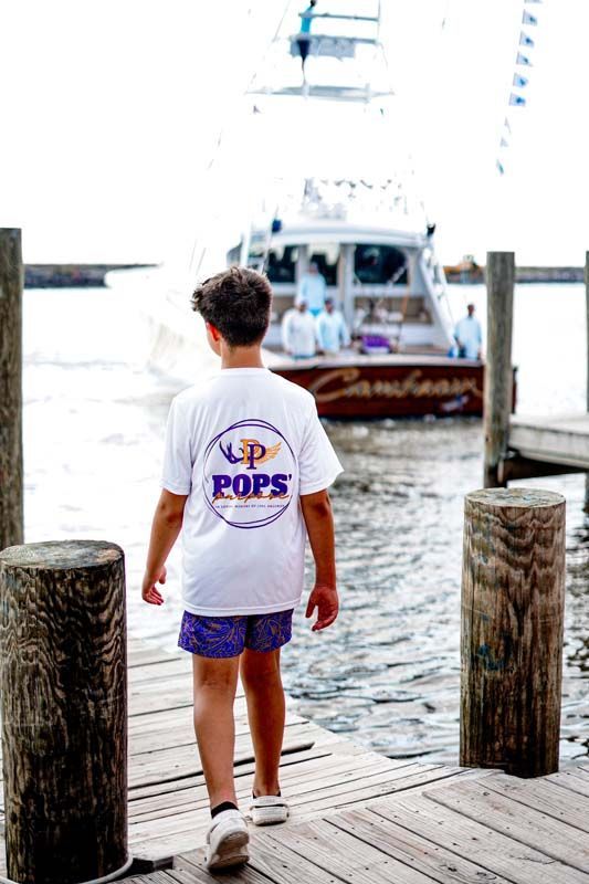 A young boy is walking on a dock towards a boat.