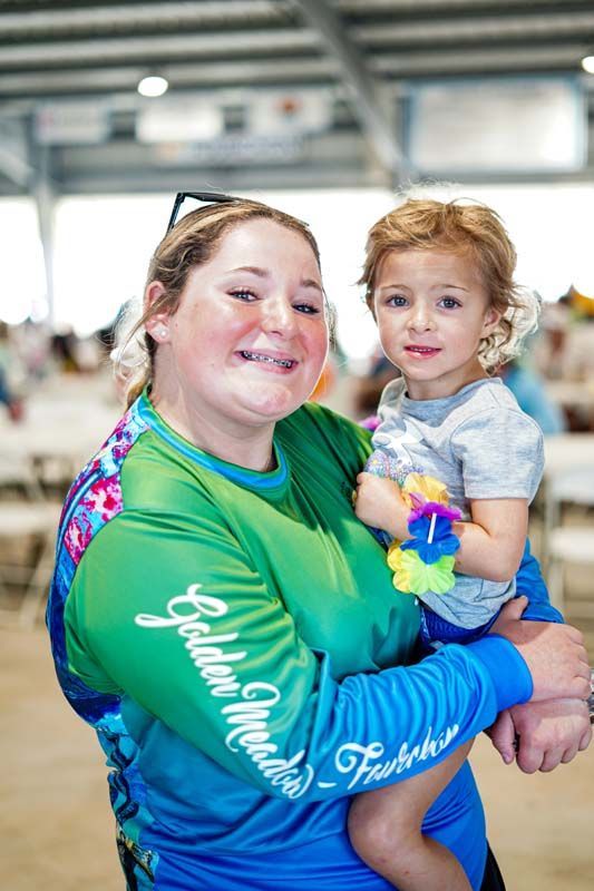 A woman in a green shirt is holding a baby in her arms.