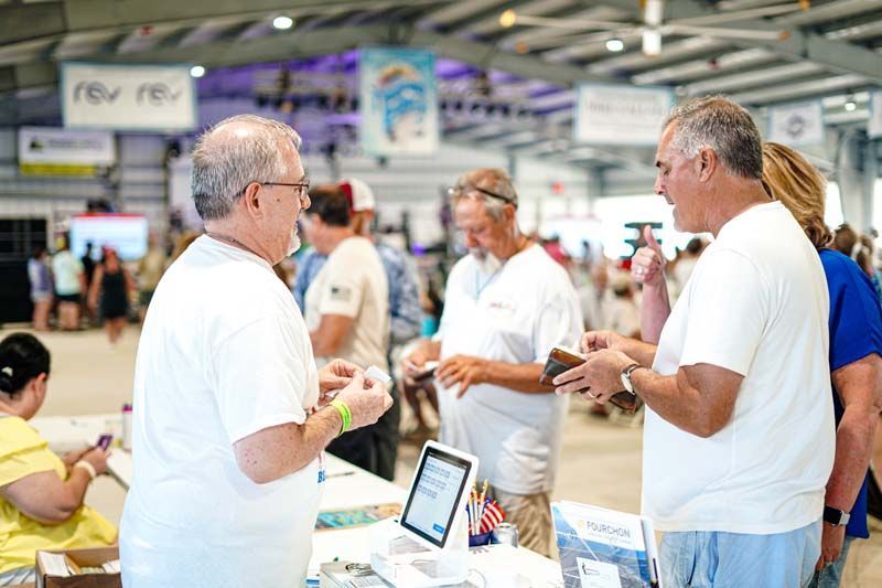 A group of men are standing around a table talking to each other.