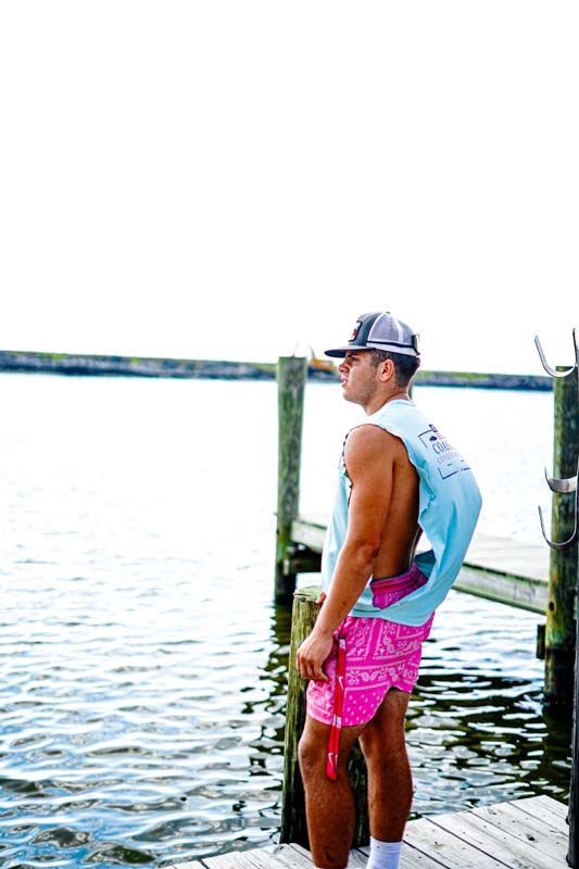 A man is standing on a dock next to a body of water.