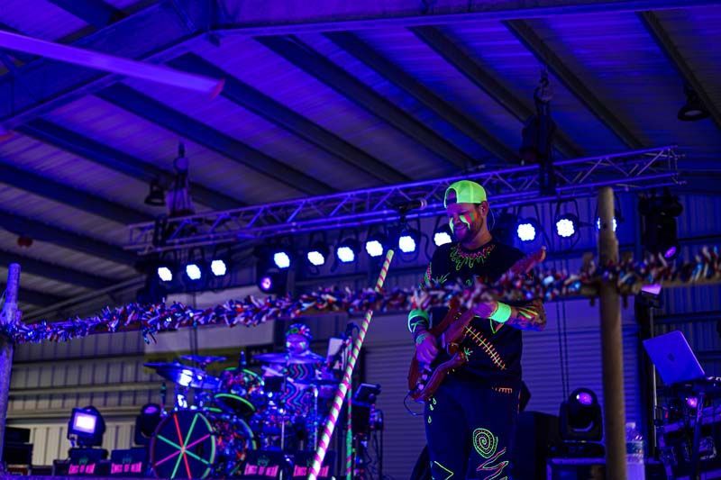 A man is playing a guitar on a stage in a dark room.