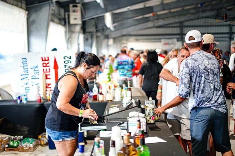 A woman is standing at a table in front of a crowd of people.