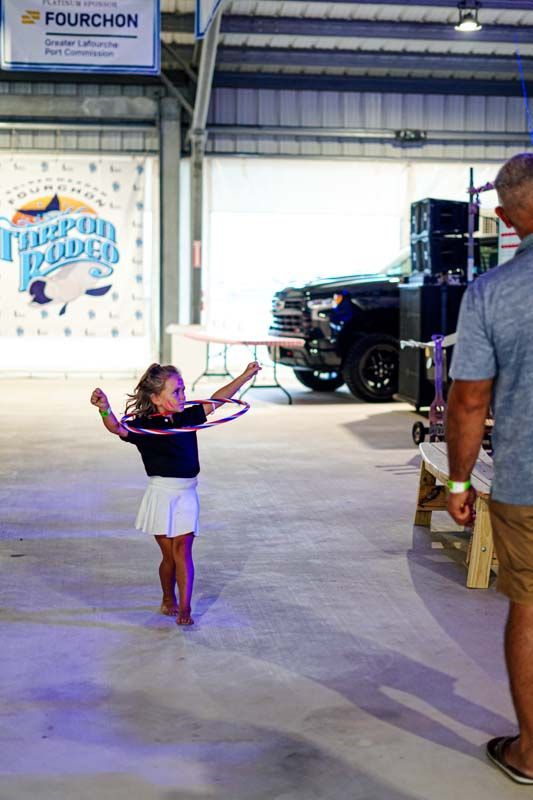 A little girl is playing with a hula hoop while a man watches.