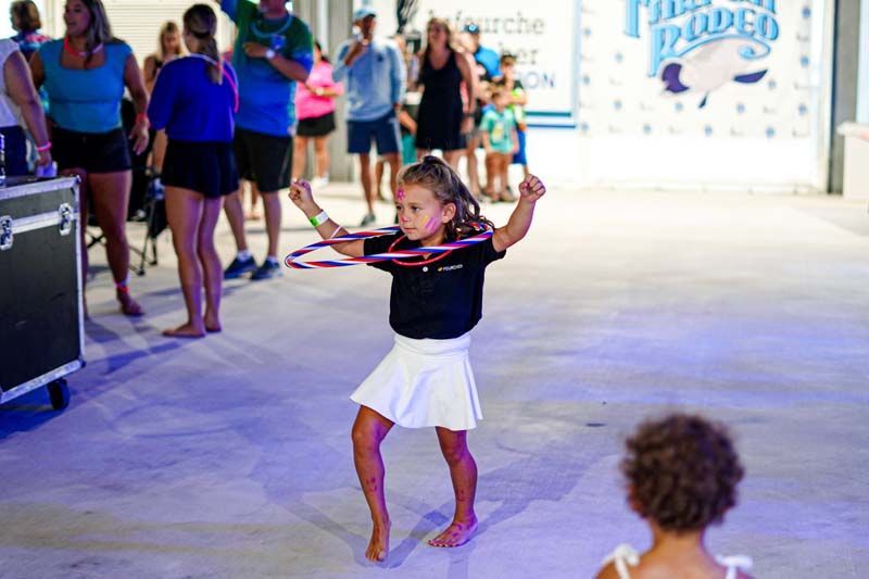 A little girl is dancing with a hula hoop in front of a crowd.