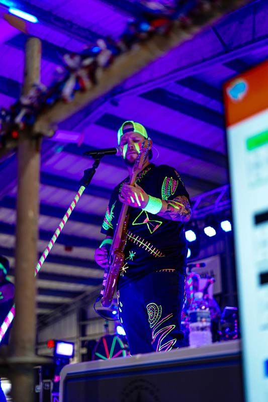 A man is standing on a stage playing a guitar and singing into a microphone.