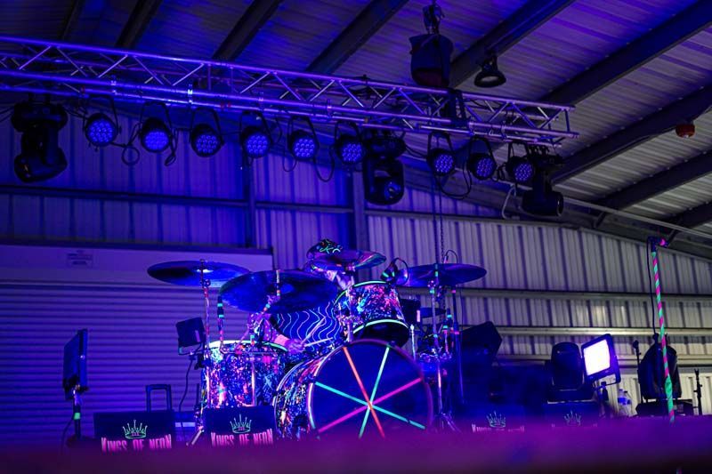A drum set is sitting on a stage in a building with purple lights.