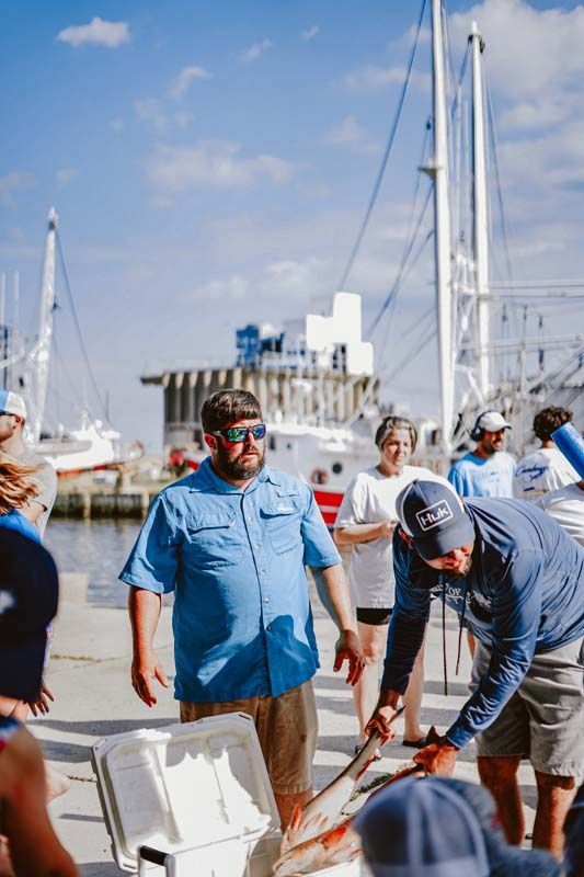 A group of men are standing around a boat in a harbor.