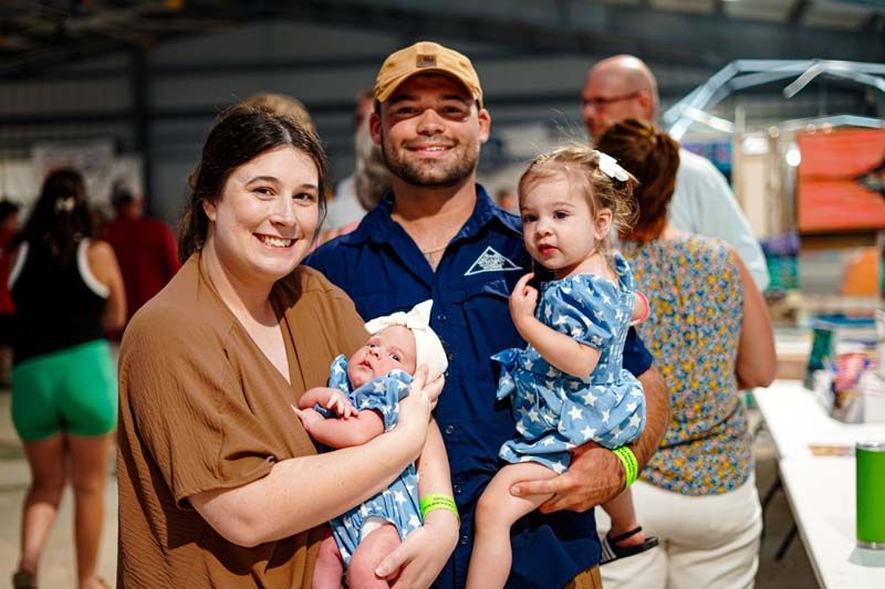 A man and woman are holding a baby and a little girl.