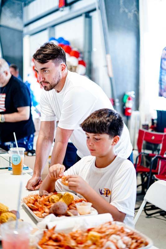 A man and a boy are sitting at a table eating shrimp.