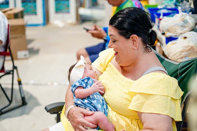 A woman is holding a baby in her arms while sitting in a chair.