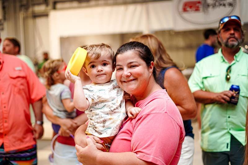 A woman is holding a baby in her arms in a crowd of people.