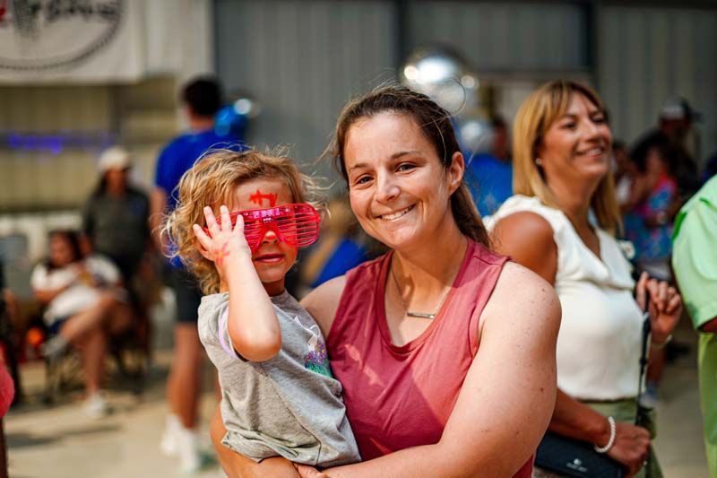 A woman is holding a little girl wearing sunglasses.