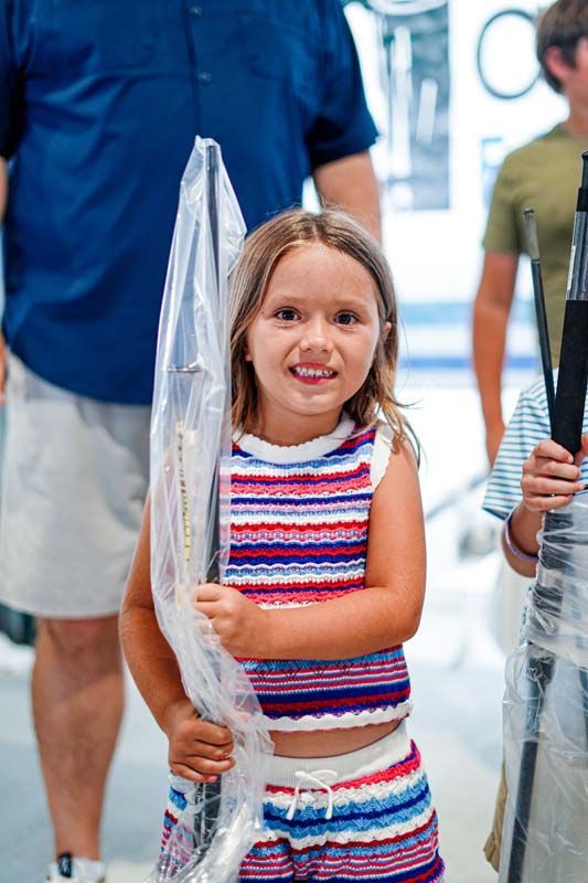 A little girl is holding an umbrella in a plastic bag.