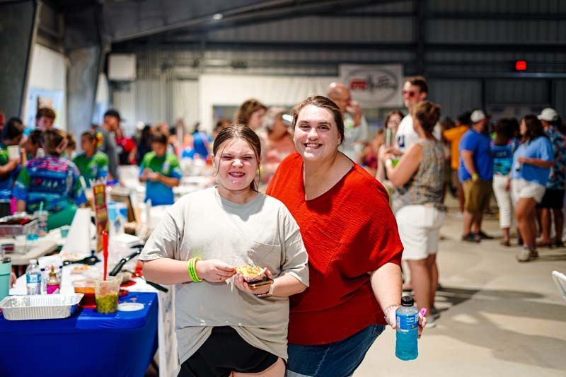 Two women are posing for a picture in front of a crowd at a festival.