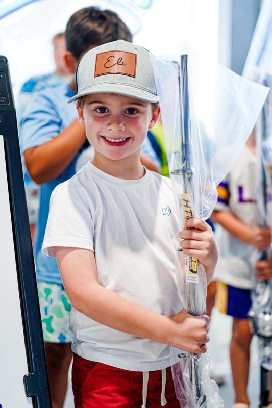 A young boy wearing a hat is holding a fishing rod.