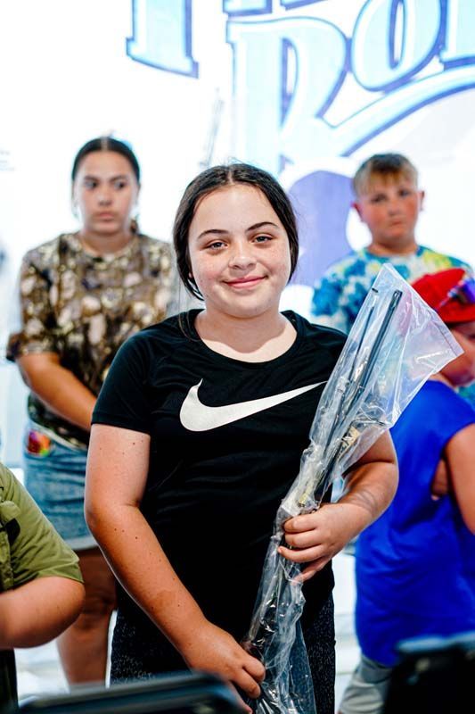 A girl in a black nike shirt is holding a tennis racket.