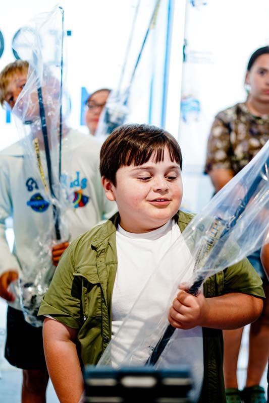 A boy in a green shirt is holding a plastic bag over his head.