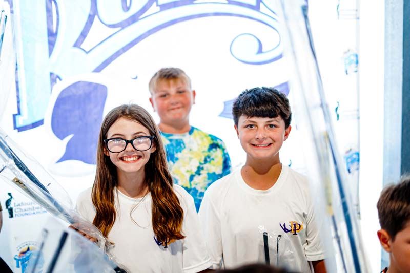 A group of children are standing next to each other in front of a sign.