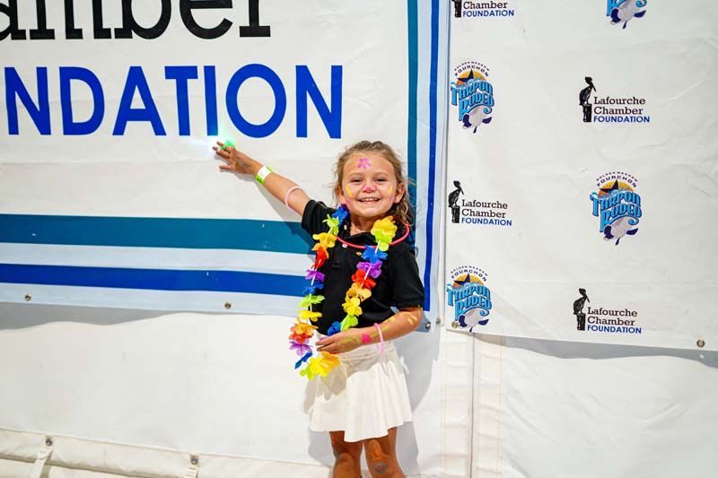 A little girl is standing in front of a sign that says ndation.