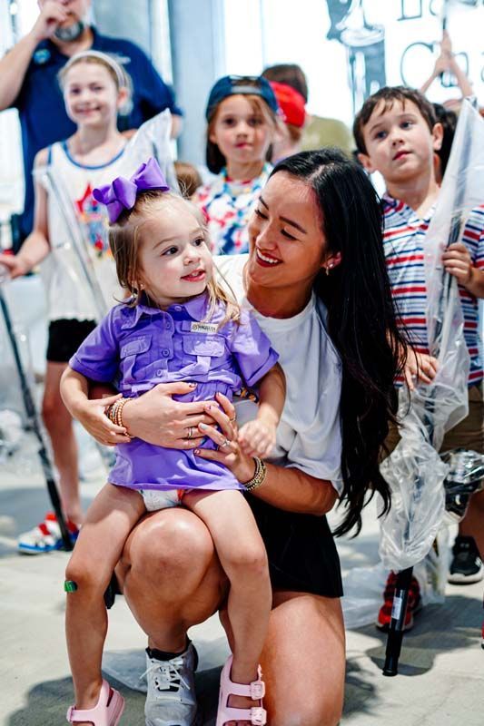 smiling little girl in purple shirt bouncing on woman's lap