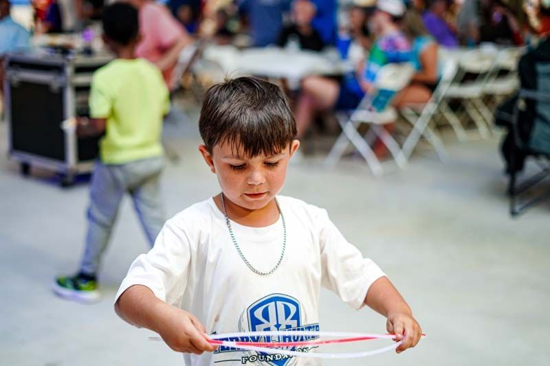 A young boy is playing with a hula hoop at a party.