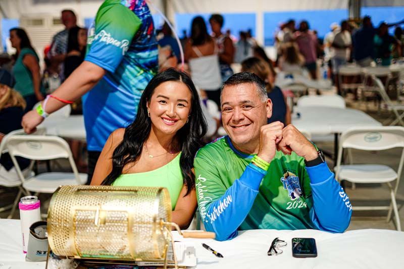 A man and a woman are sitting at a table in front of a lottery machine.