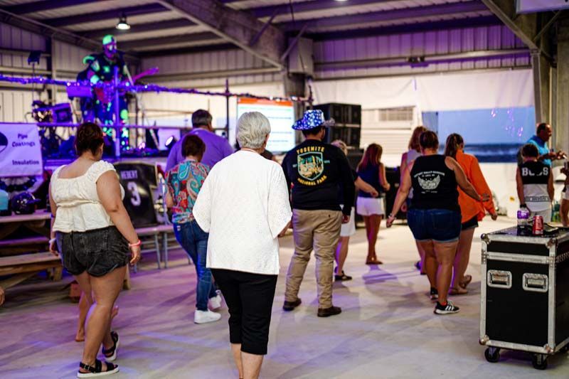 A group of people are dancing in a room with purple lights.