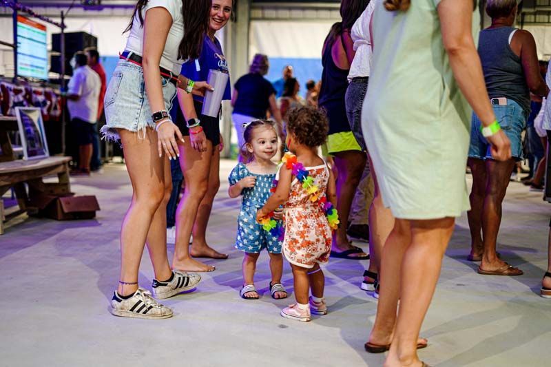A little girl is standing next to a woman in a crowd of people.