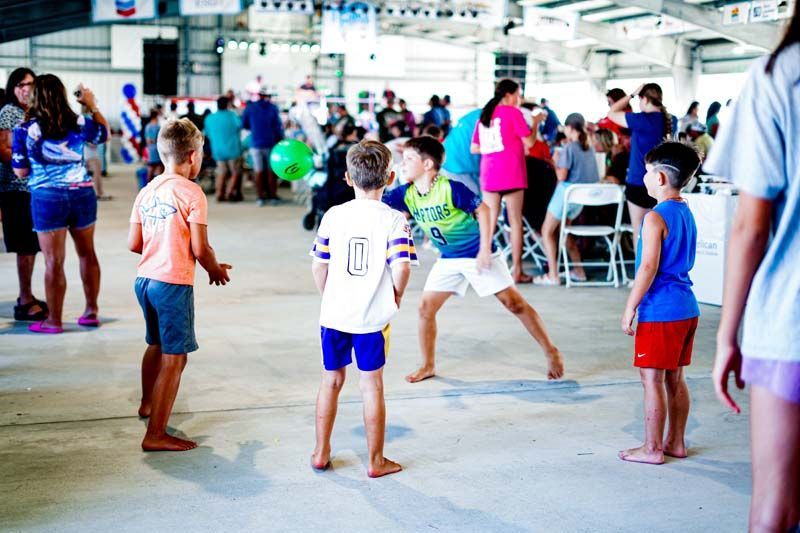 A group of children are playing volleyball in a large room.