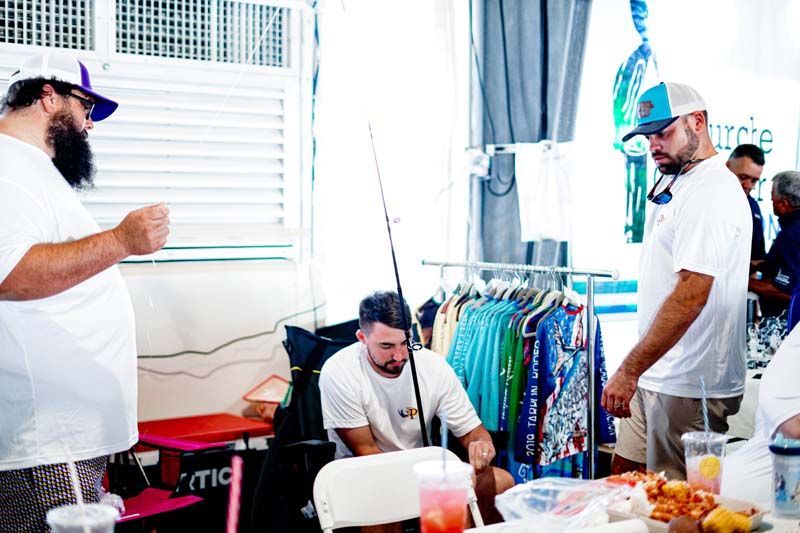 A group of men are standing around a table with a fishing rod.