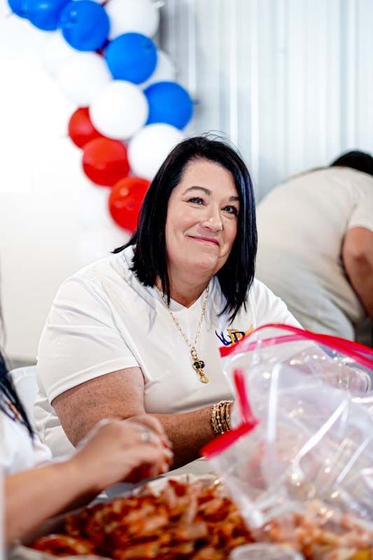 A woman is sitting at a table with a bag of food.