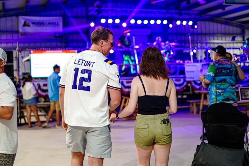 A man and a woman are standing in front of a stage at a concert.