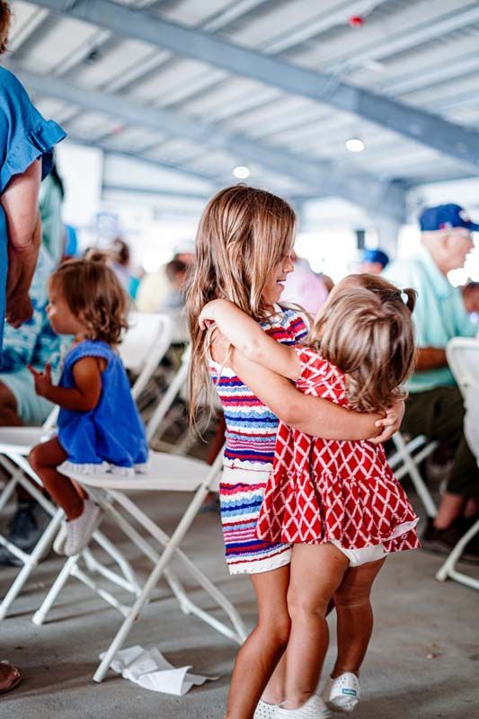 Two little girls are hugging each other at a party.